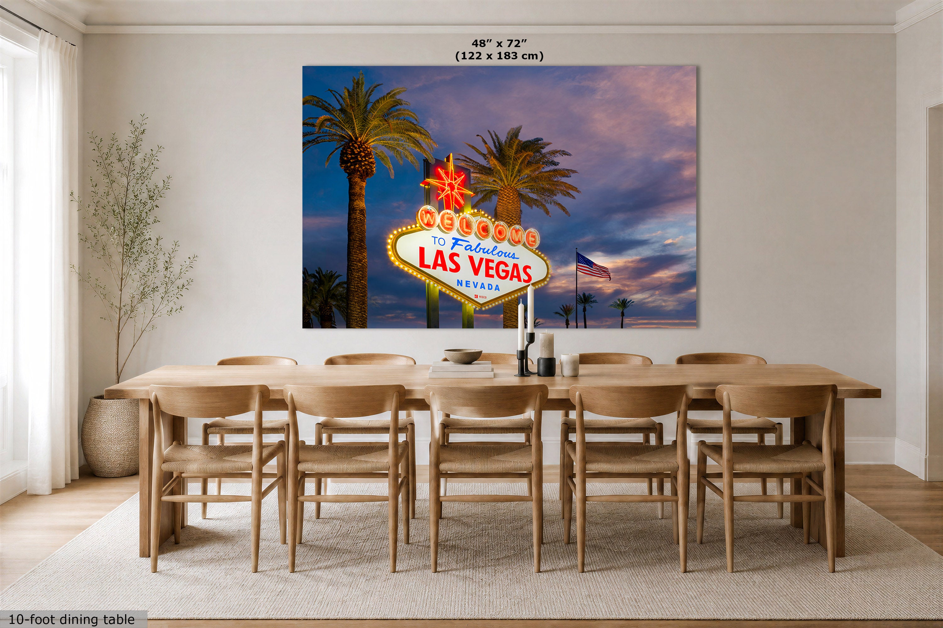 A large wall art print of the Las Vegas sign with palm trees and a sunset sky, displayed above a wooden dining table in a modern dining room. The print includes size text at the top reading 48" x 72" (122 x 183 cm).
