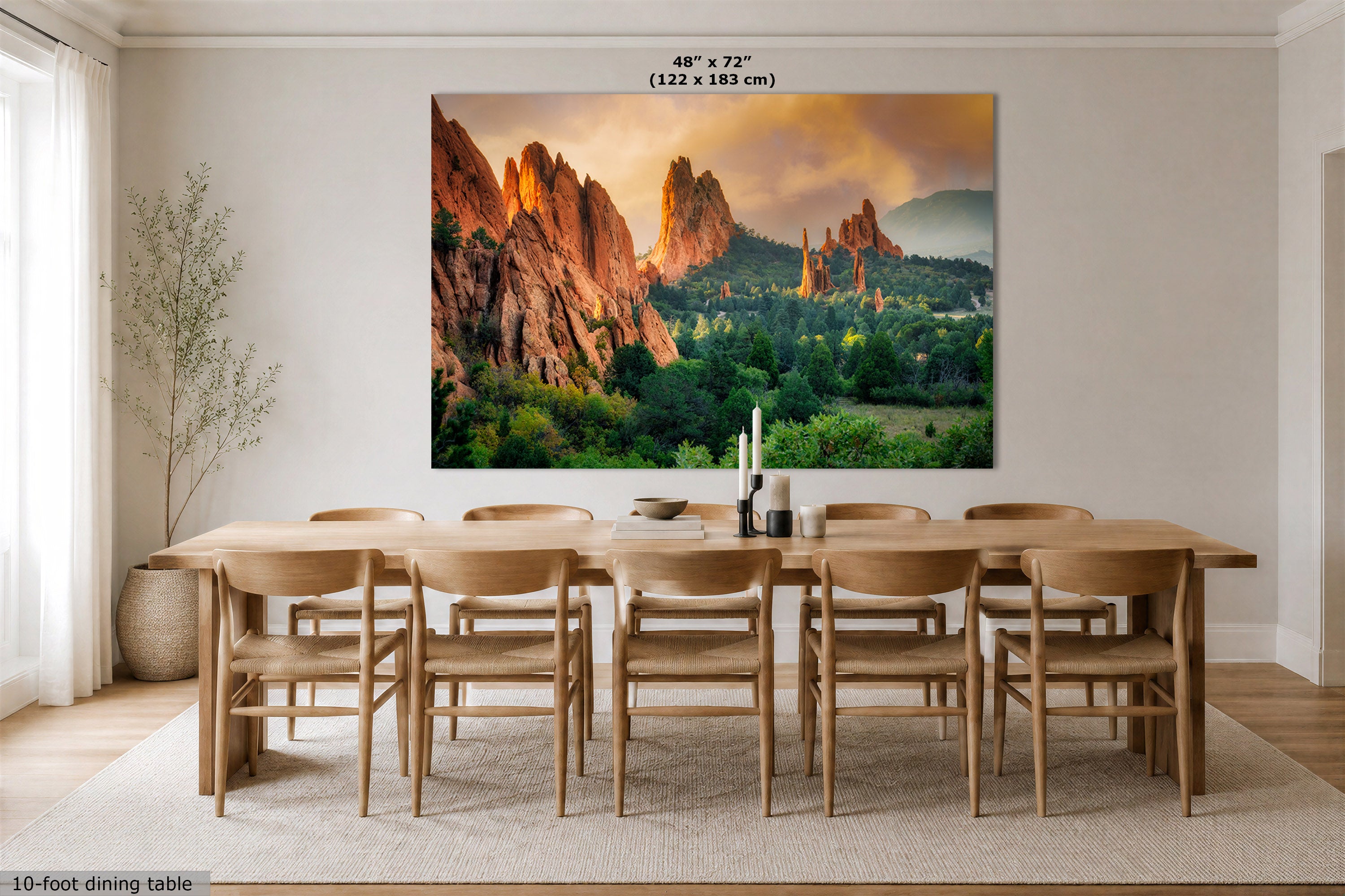 A large wall art print depicting a dramatic desert canyon landscape with orange rock formations and green trees, displayed above a wooden dining table in a bright, modern dining room. The print includes a size label at the top reading 48" x 72" (122 x 183 cm).