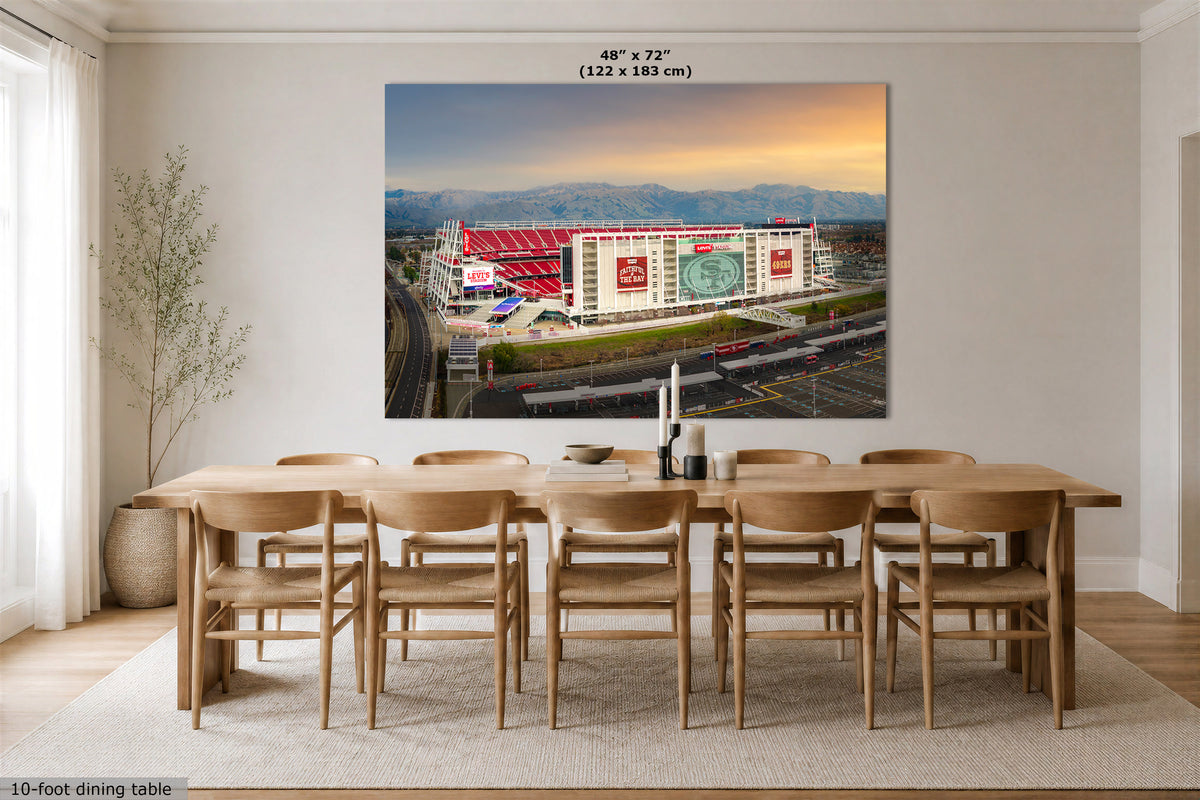 A large San Francisco 49ers Stadium art print showing an aerial view of the Levi's stadium at sunset, displayed above a wooden dining table in a bright modern dining room. The print includes size text at the top reading 48" x 72" (122 x 183 cm).