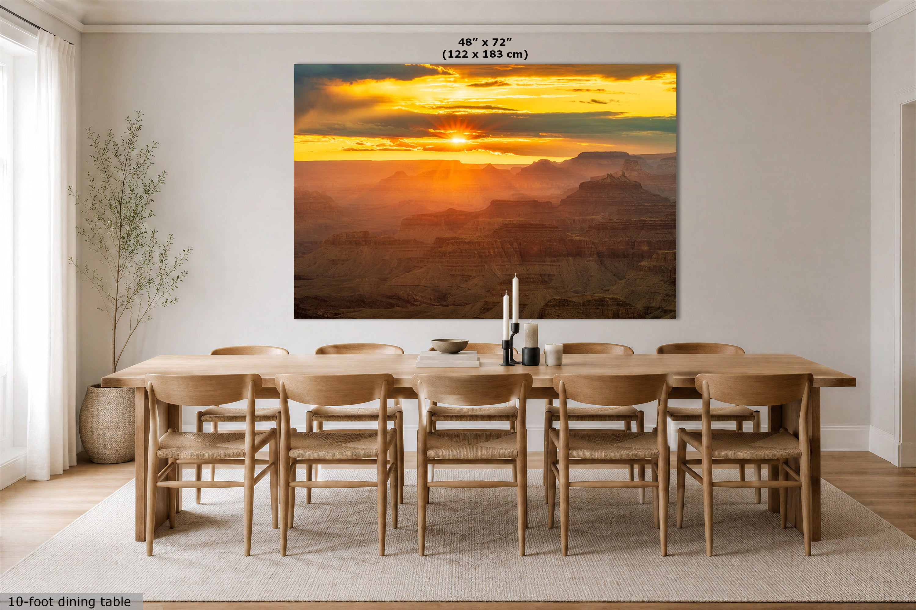 A large rectangular wall art print showing a Grand Canyon sunset hangs above a wooden dining table and chairs in a bright dining room. The print includes text at the top reading 48" x 72" (122 x 183 cm) and the scene itself is the product being sold.
