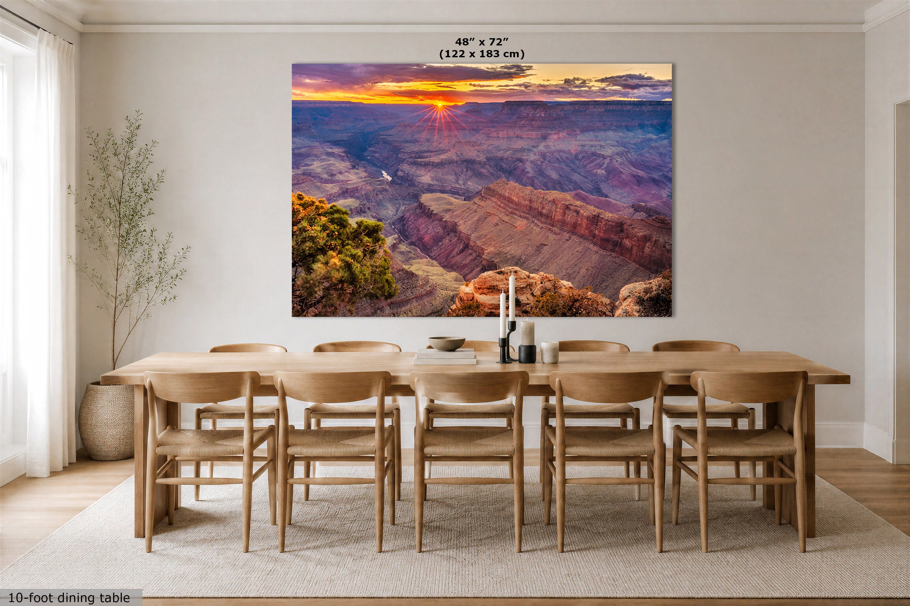 A large rectangular wall art print showing a Grand Canyon sunset hangs above a wooden dining table and chairs in a bright, modern dining room. The print includes size text at the top reading 48" x 72" (122 x 183 cm).