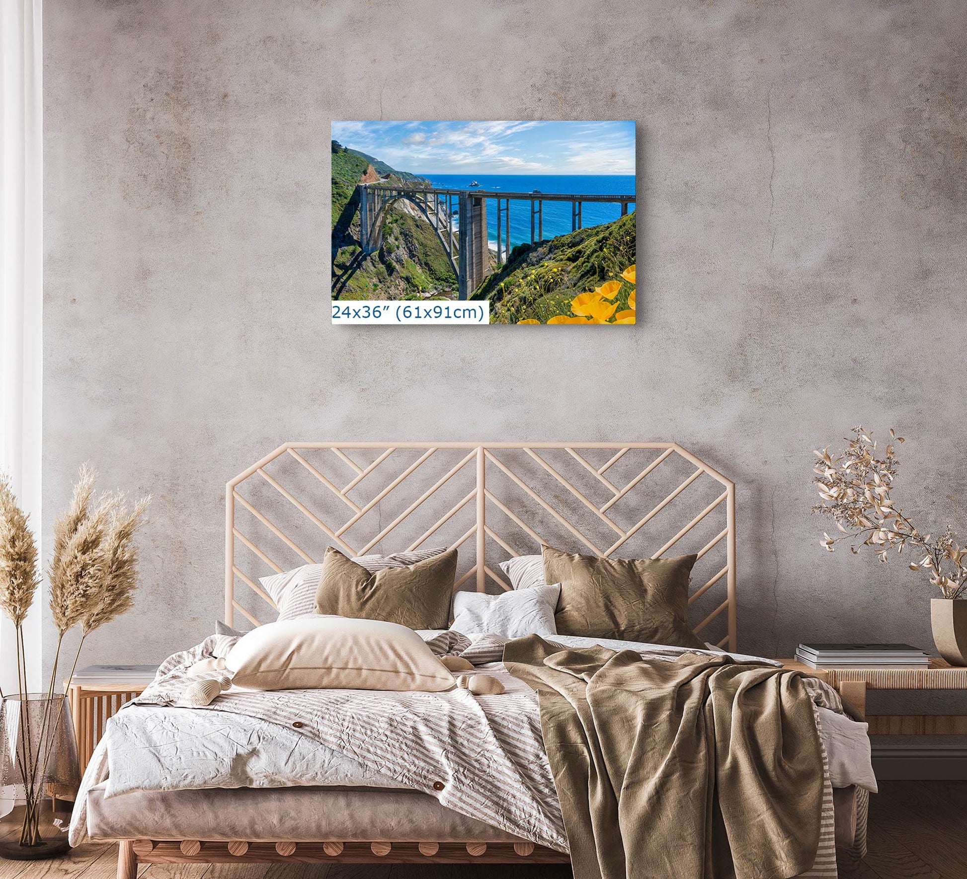 Wall art photograph of Bixby Bridge on the Big Sur coast of California, displayed above a bed in a cozy bedroom setting, size 24x36 inches