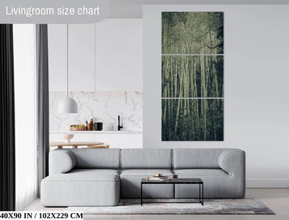 A 40x90-inch vertical triptych canvas print in a modern living room, with a duotone image of aspen birch trees, evoking a silent, eerie forest.