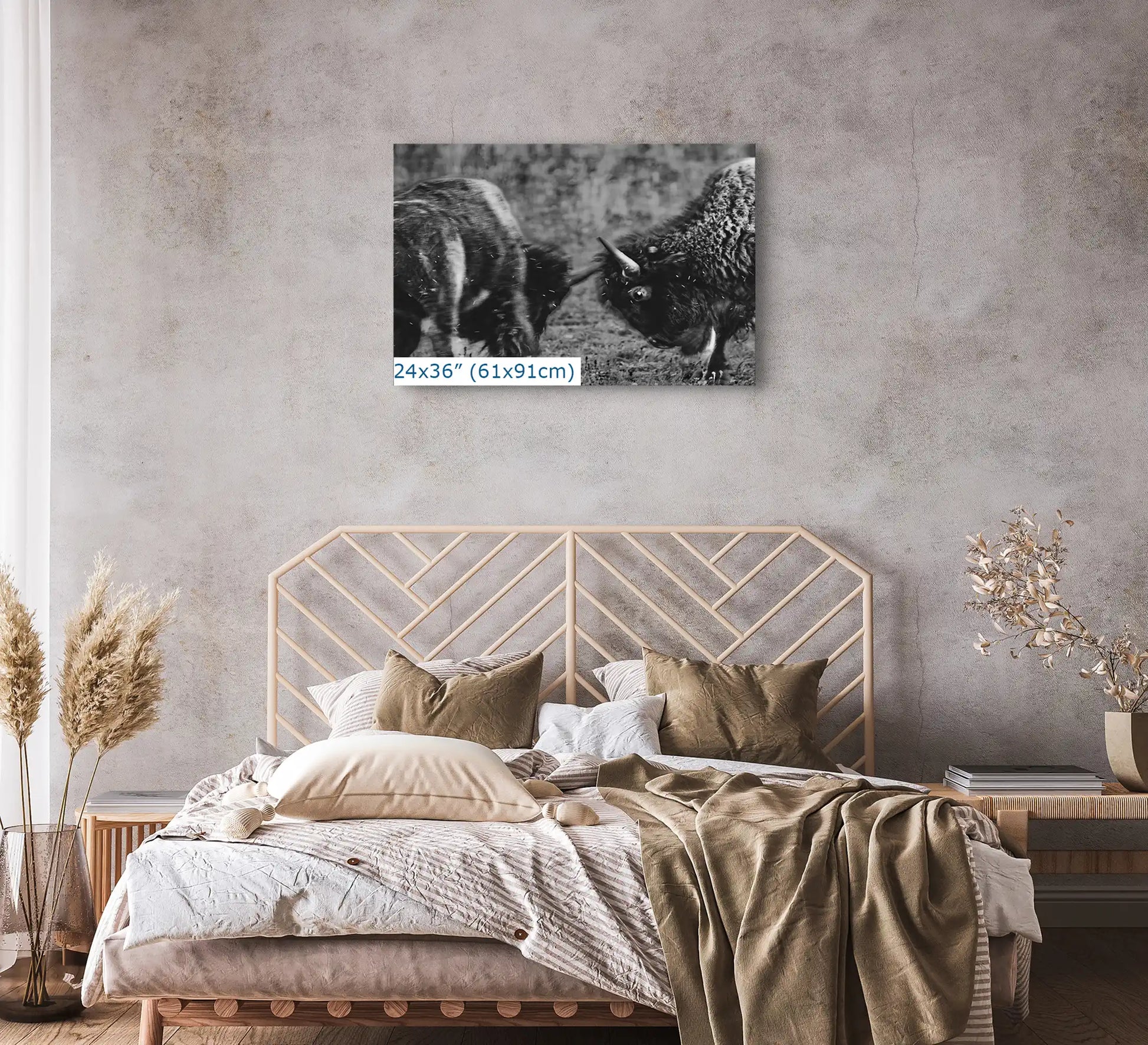 A large 24x36 inch canvas print in black and white, depicting dueling bison, centered above a bed with neutral bedding in a bedroom setting.