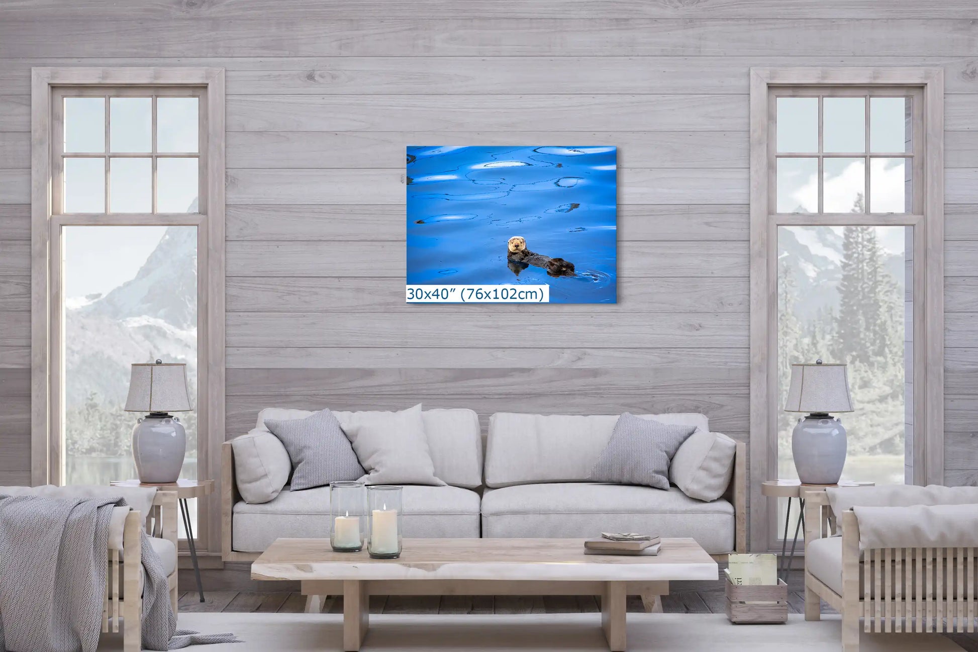 A 30"x40" canvas depicting a sea otter in tranquil water, creating a focal point above a living room sofa with a mountain view outside.