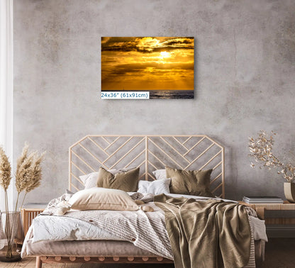 A 24"x36" canvas print showcasing a California sunset, hung above a bed, contributing to the tranquil decor of the bedroom.