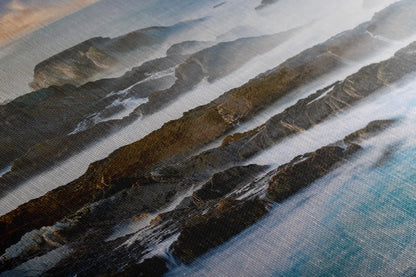 Textured canvas close-up of the California Pacific coastline with sunlight casting over the rocky shores, showcasing fine print quality.