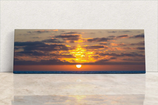Image of a gallery-wrapped canvas print of an ocean sunset with vibrant yellow and orange hues reflected on the water.