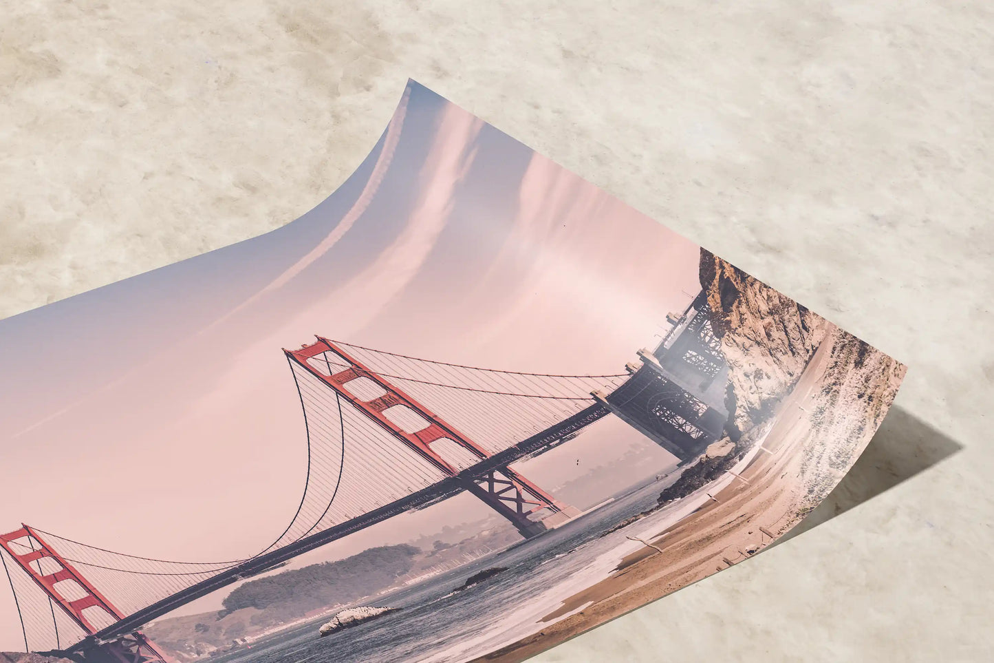 Curled corner of a vintage-style print depicting the Golden Gate Bridge in warm hues, ideal for classic San Francisco-themed wall decor.