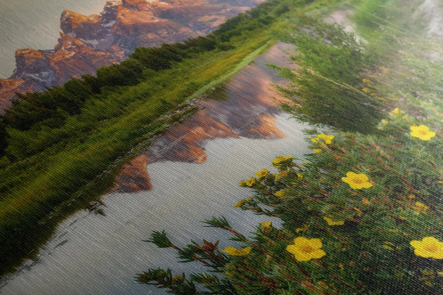 Close-up of the textured surface of a canvas print showing the Grand Teton Mountains at sunrise with vibrant wildflowers in the foreground.