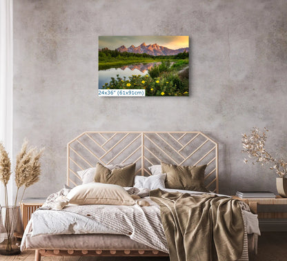A 24x36 inch canvas print above a bed, featuring the Grand Teton Mountains at sunrise with yellow wildflowers, blending with the bedrooms decor.