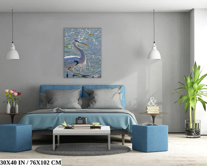 A 30x40 inch canvas print of a great blue heron above a bed with blue accents, illustrating the impact of wall art in bedroom design.