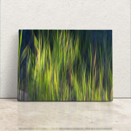 A canvas print resting against a wall, displaying a vibrant sage green abstract photograph of blurred grass, creating an impressionistic nature decoration.