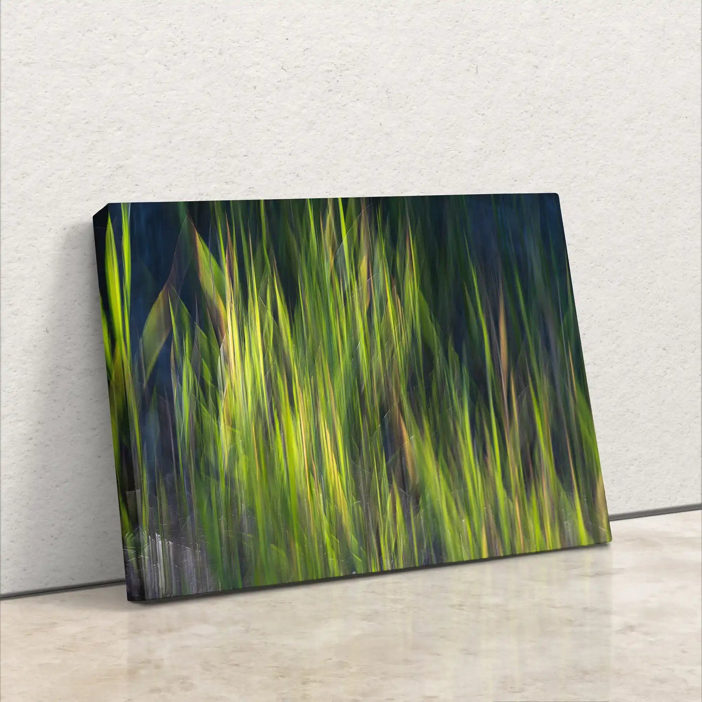 A canvas print leaning against a white wall, featuring abstract green and yellow vertical brushstrokes giving an impression of blurred grass or foliage.