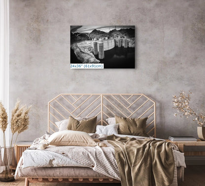 A 24x36 canvas of Hoover Dam in black and white, placed above a bed, serving as a bold centerpiece in a bedroom setting.