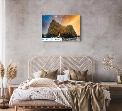A 24"x36" wall art in a bedroom setting, showing the Keyhole Arch at Big Sur with a dramatic sunset, creating a peaceful and majestic ambiance.
