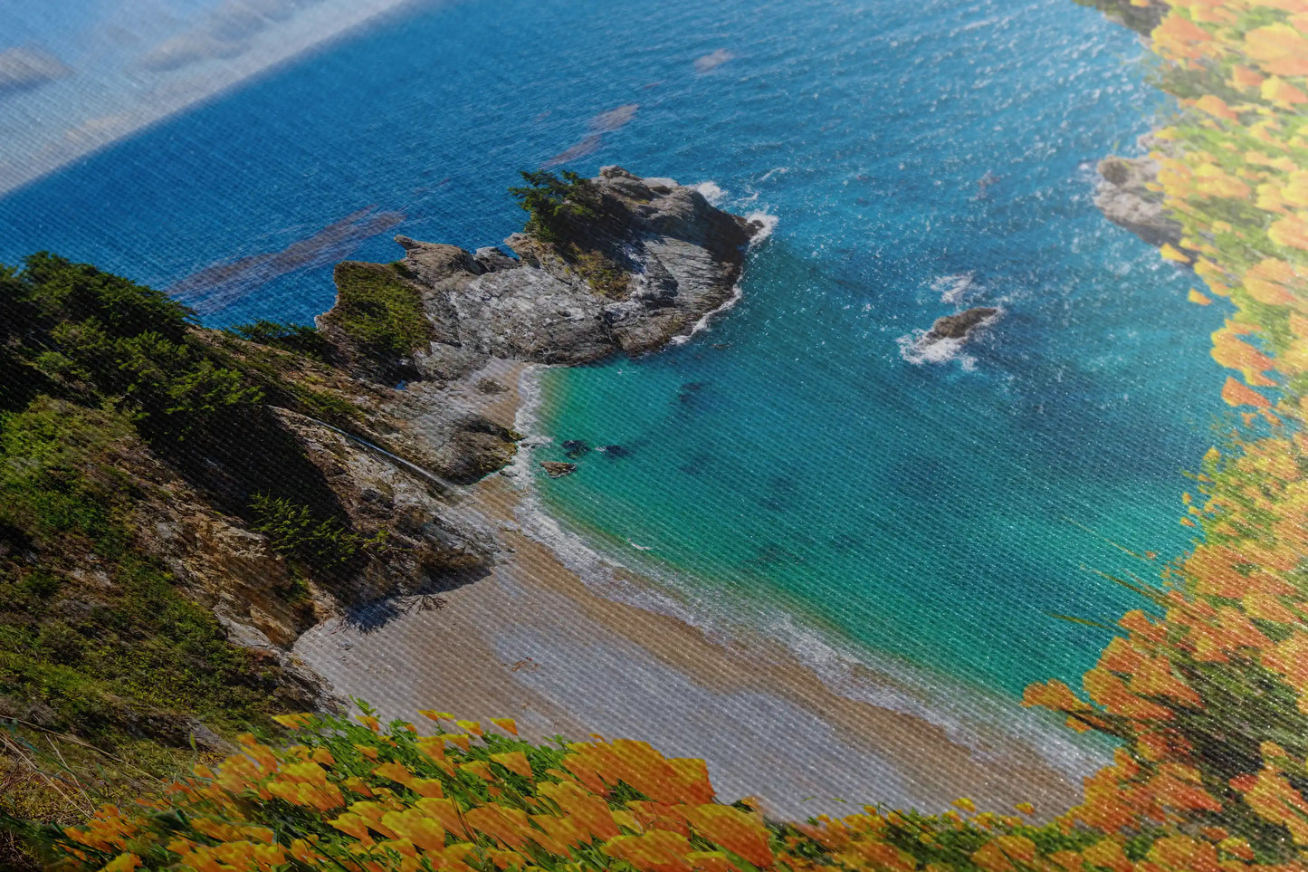 Detailed close-up of canvas wall art texture with the image of McWay Falls at Big Sur, accentuating the orange wildflowers and turquoise sea.