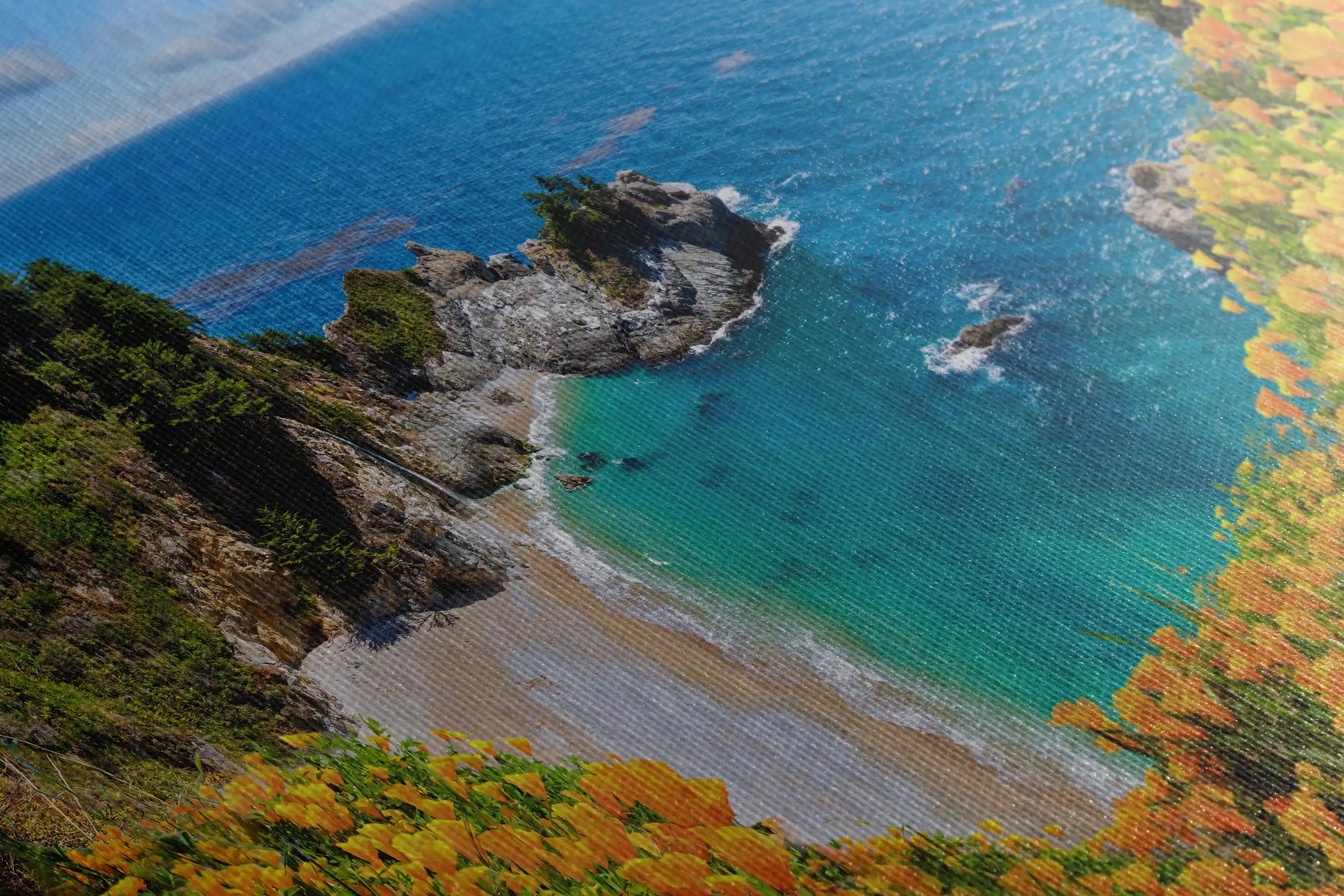 Detailed close-up of canvas wall art texture with the image of McWay Falls at Big Sur, accentuating the orange wildflowers and turquoise sea.