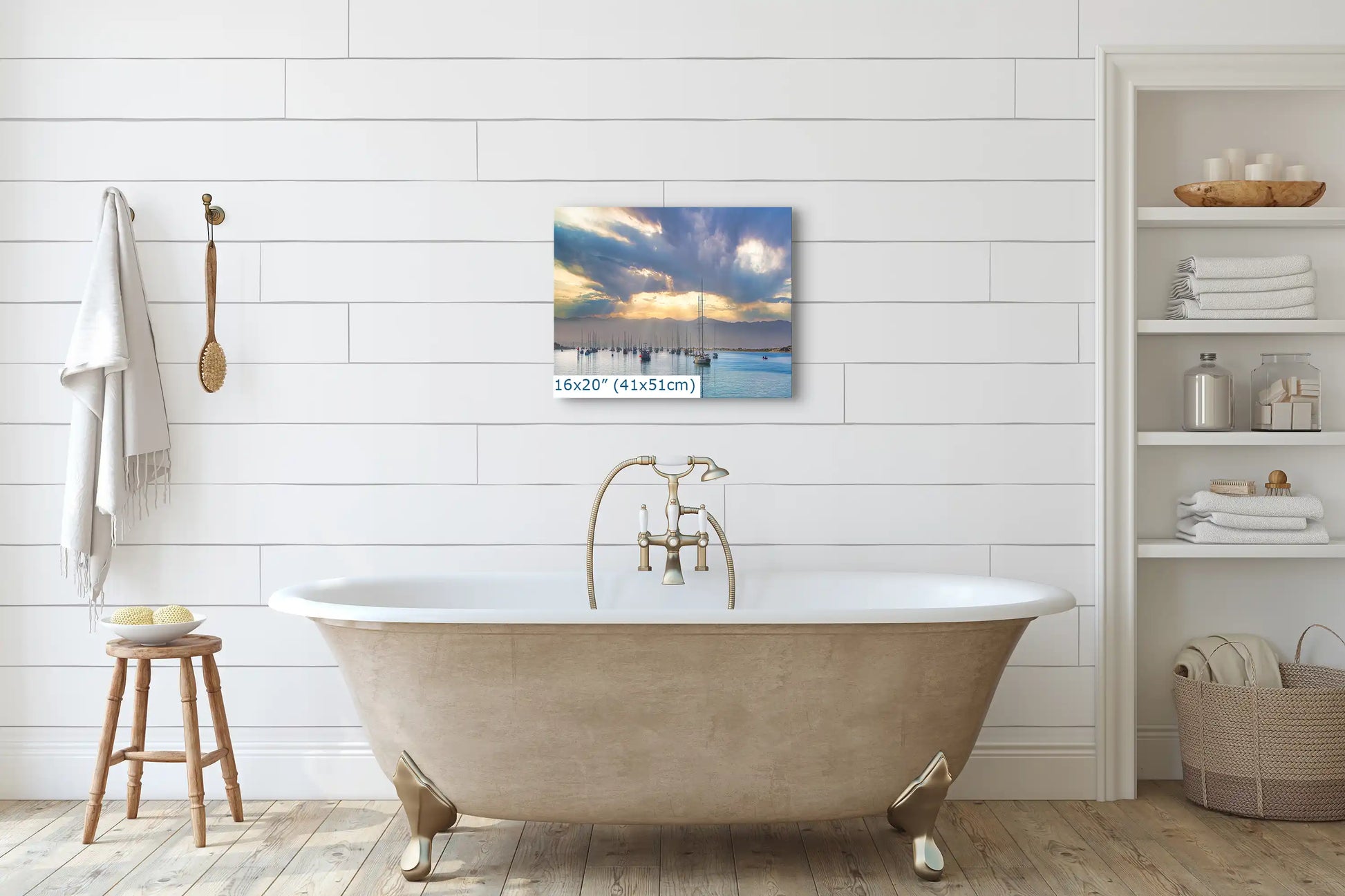 A 16x20 inch canvas print above a bathtub, showing a tranquil harbor with sun rays piercing through clouds at dawn.