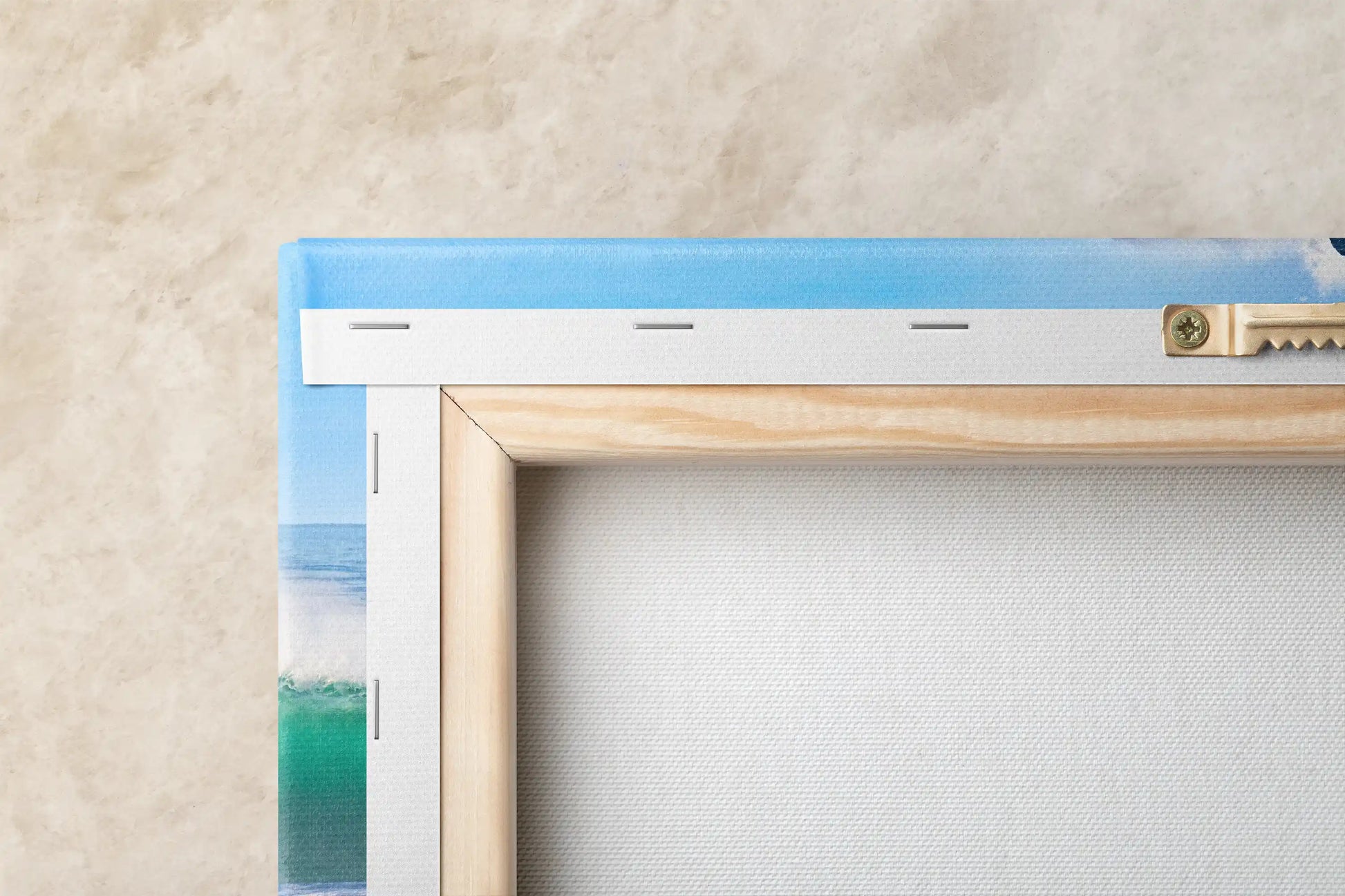 Close-up of the back corner of a canvas print, showing the wooden frame and the canvas texture against a textured wall.