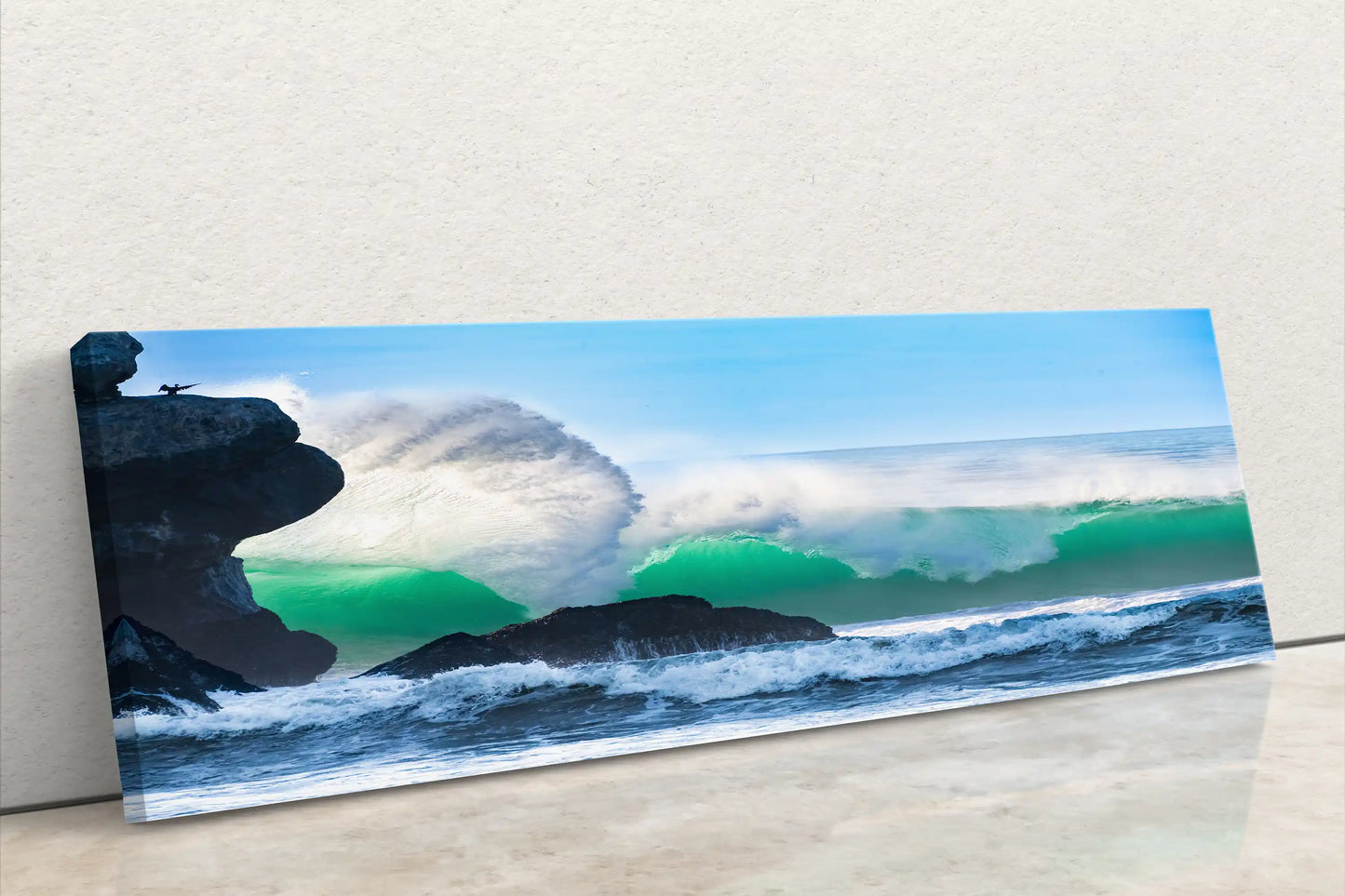 Side view of a panoramic canvas wall art showing an impressive ocean wave by Morro Rock, emphasizing the depth of the canvas on a white wall.