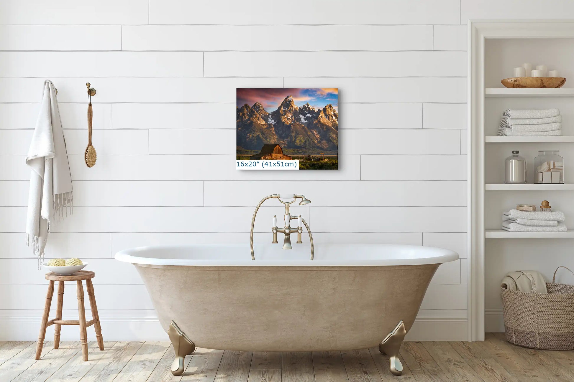 A 16x20 canvas print above a bathtub, depicting the John Moulton Homestead with the Teton Mountains at sunrise, creating a tranquil bathroom ambiance.