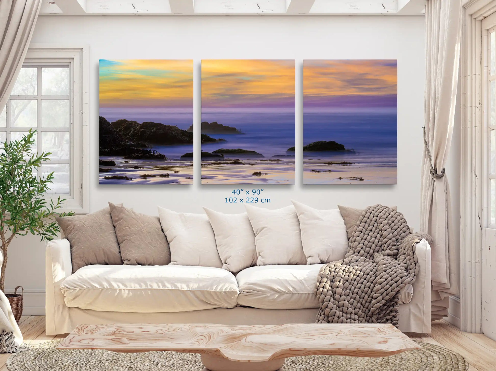 A 40x90 triptych wall art set against a couch, each panel capturing the enchanting sunset colors over Purple Sand Beach in Big Sur, for an immersive aesthetic experience.