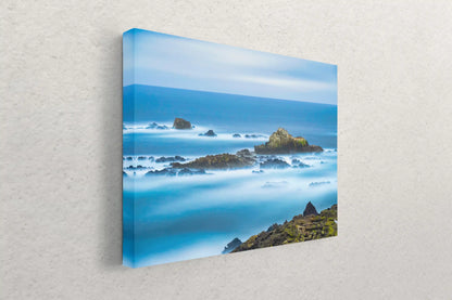 Point Lobos seascape canvas art on display, featuring ethereal blue hues of the ocean against the rocky coastline.