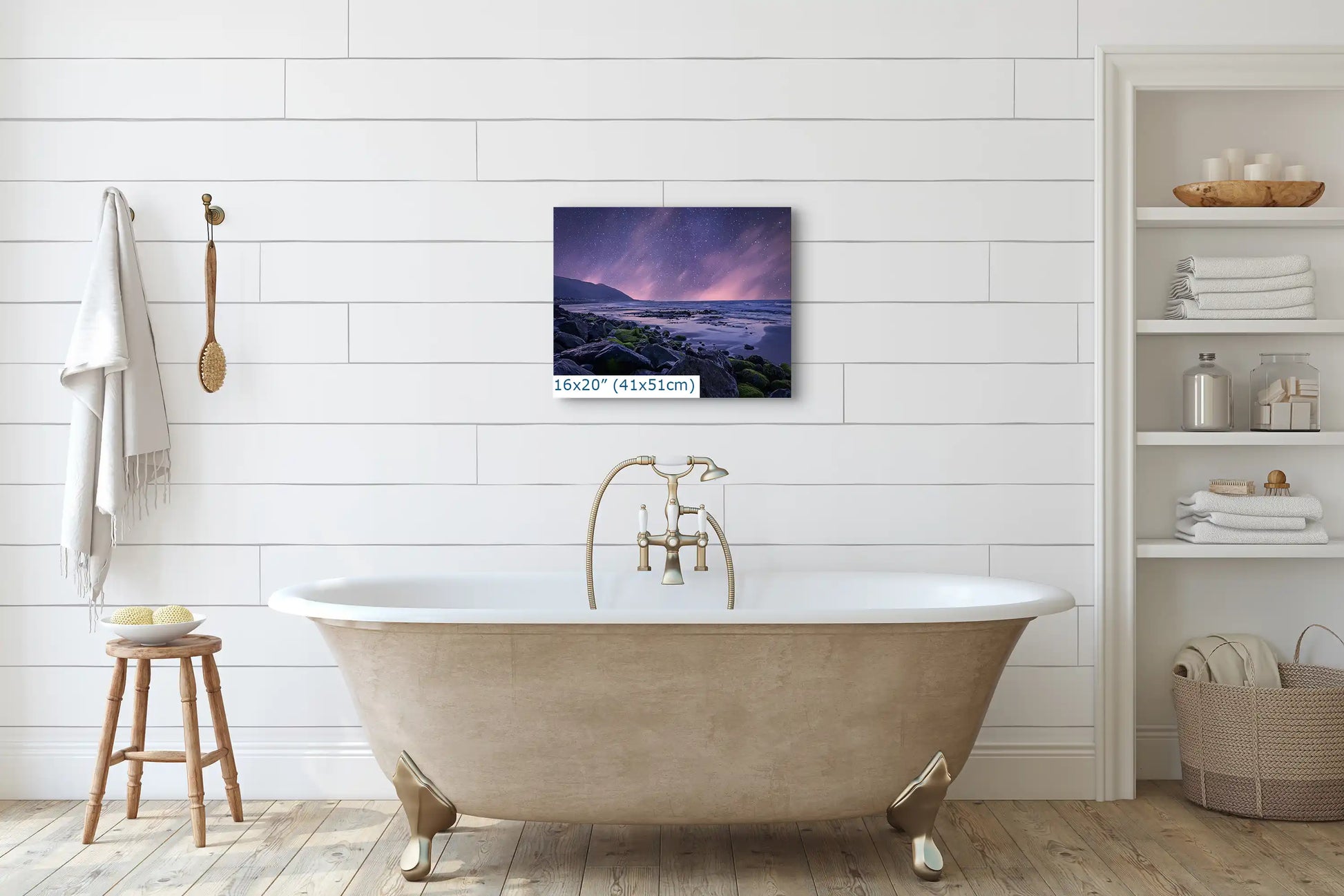 A 16x20 inch canvas print of a purple night sky over a beach, hanging on a white bathroom wall above a vintage tub.