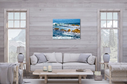 A 30"x40" canvas art of the seaside rocks and ocean scene enhancing the ambiance of a living room with a cozy sofa and mountain view.