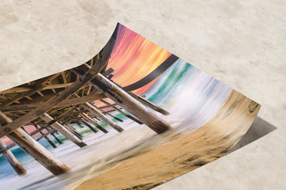 Premium paper artwork displaying a vibrant under-the-pier view of Balboa Pier at sunset, with waves and sand in sharp detail.