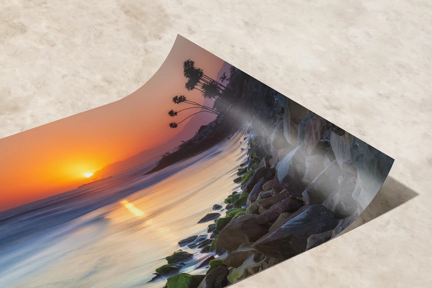 A close-up of a paper print showing the smooth curve and fine detail of Ventura Beach Sunset, highlighting the color gradient and silhouette of palm trees.