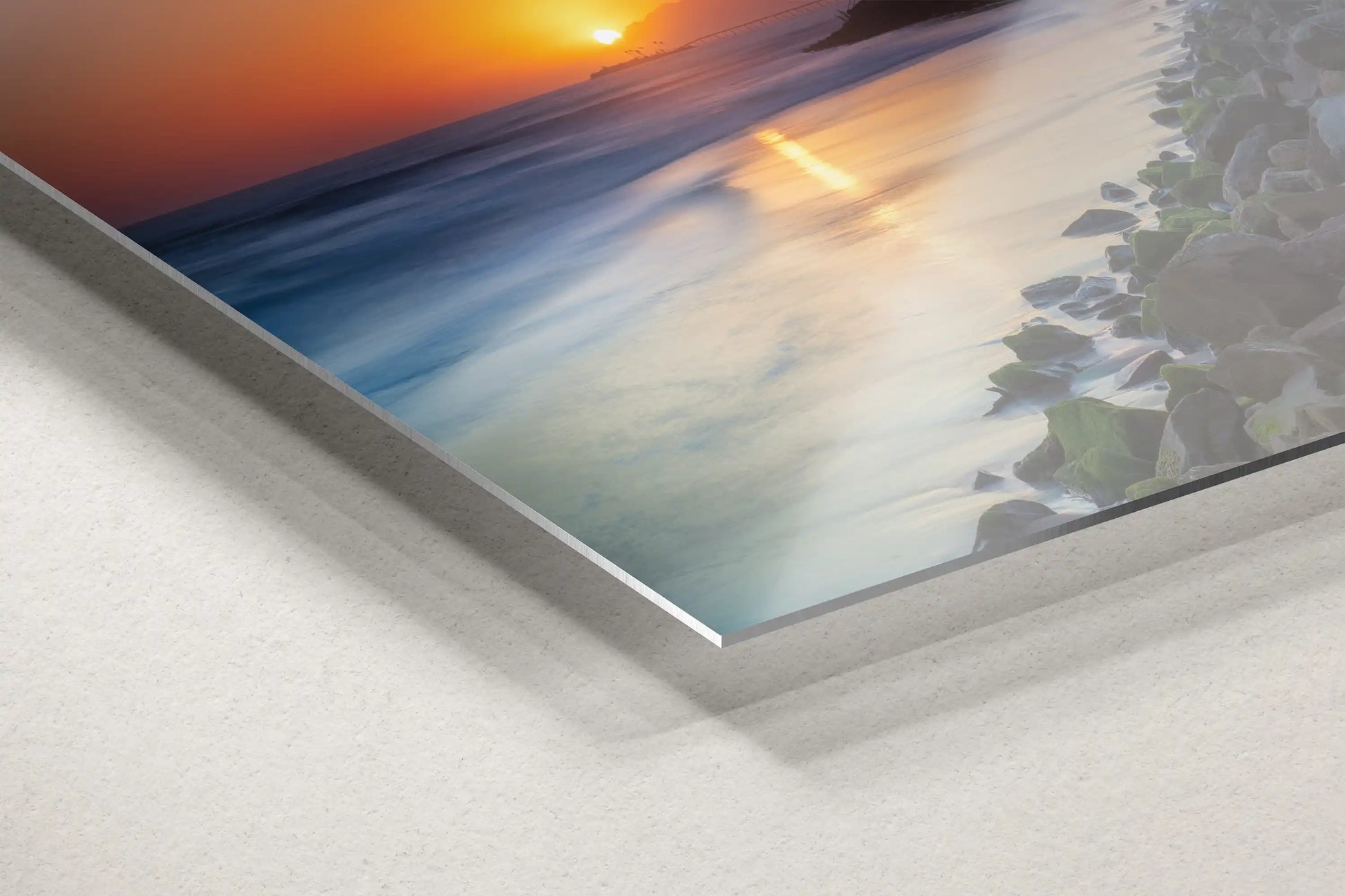 The edge of a metal print depicting Ventura Beach Sunset, with a focus on the texture and reflective quality of the material.
