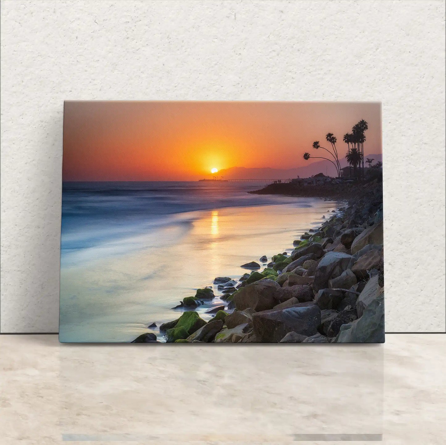 Front view of Ventura Beach sunset canvas wall art depicting the sun dipping into the ocean horizon with silhouetted palm trees.