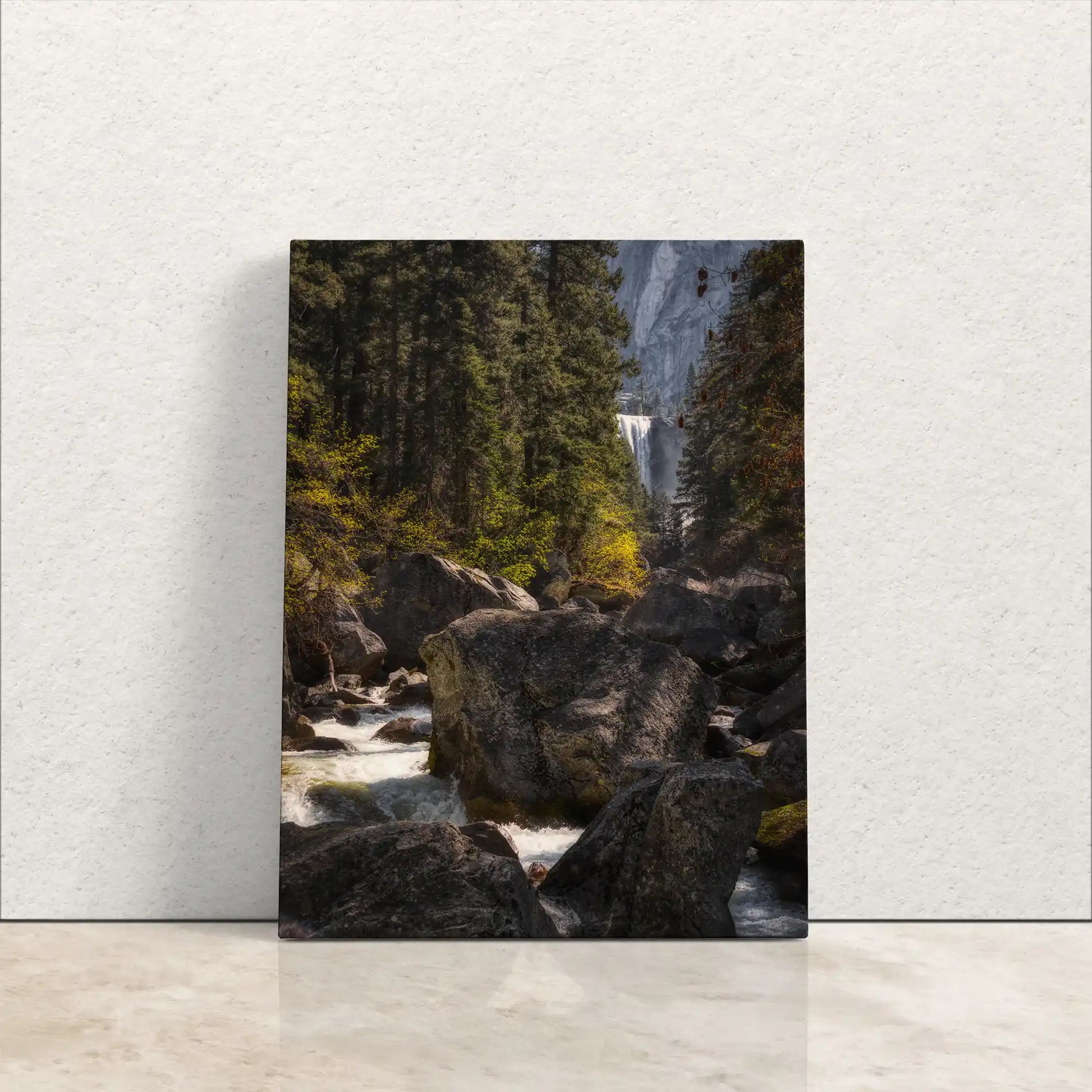 A canvas print leaning against a wall, featuring Vernal Falls and Merced River in Yosemite with lush greenery and rocks.