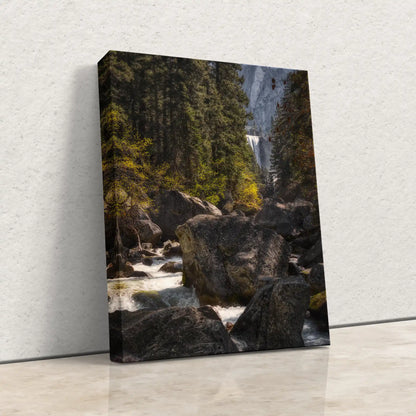 The front view of a canvas print, standing on the floor, depicting the Vernal Falls and Merced River surrounded by forest.