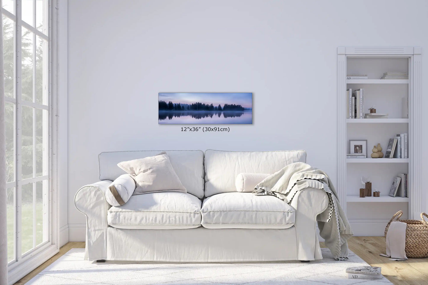 Panoramic 12x36 wall art of Yellowstone Lake's forest in twilight reflection, above a cozy white sofa, adding tranquility to the living space.