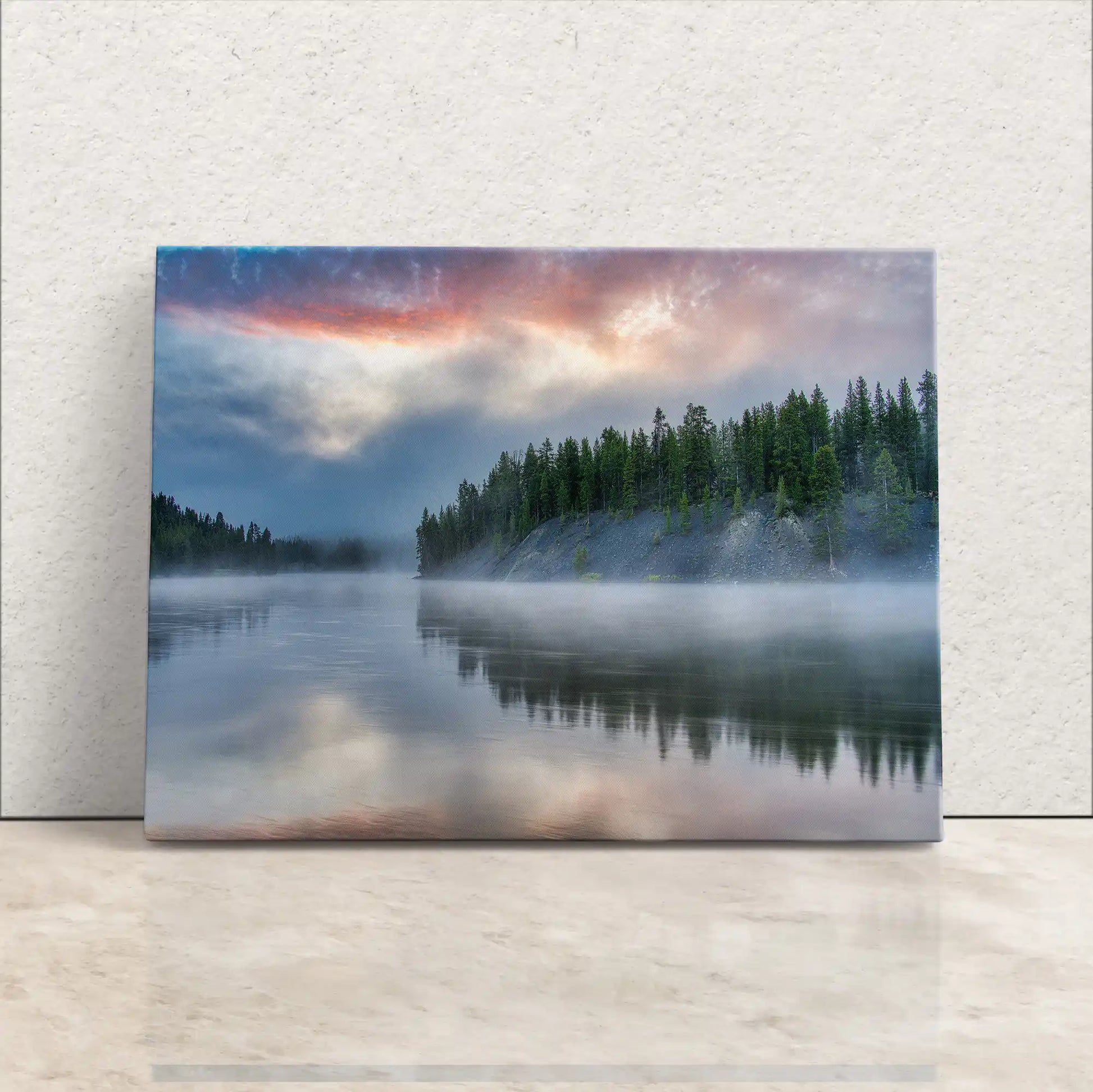 Gallery-wrapped canvas of Yellowstone Lake at sunrise reflecting a foggy forest, leaning against a wall.