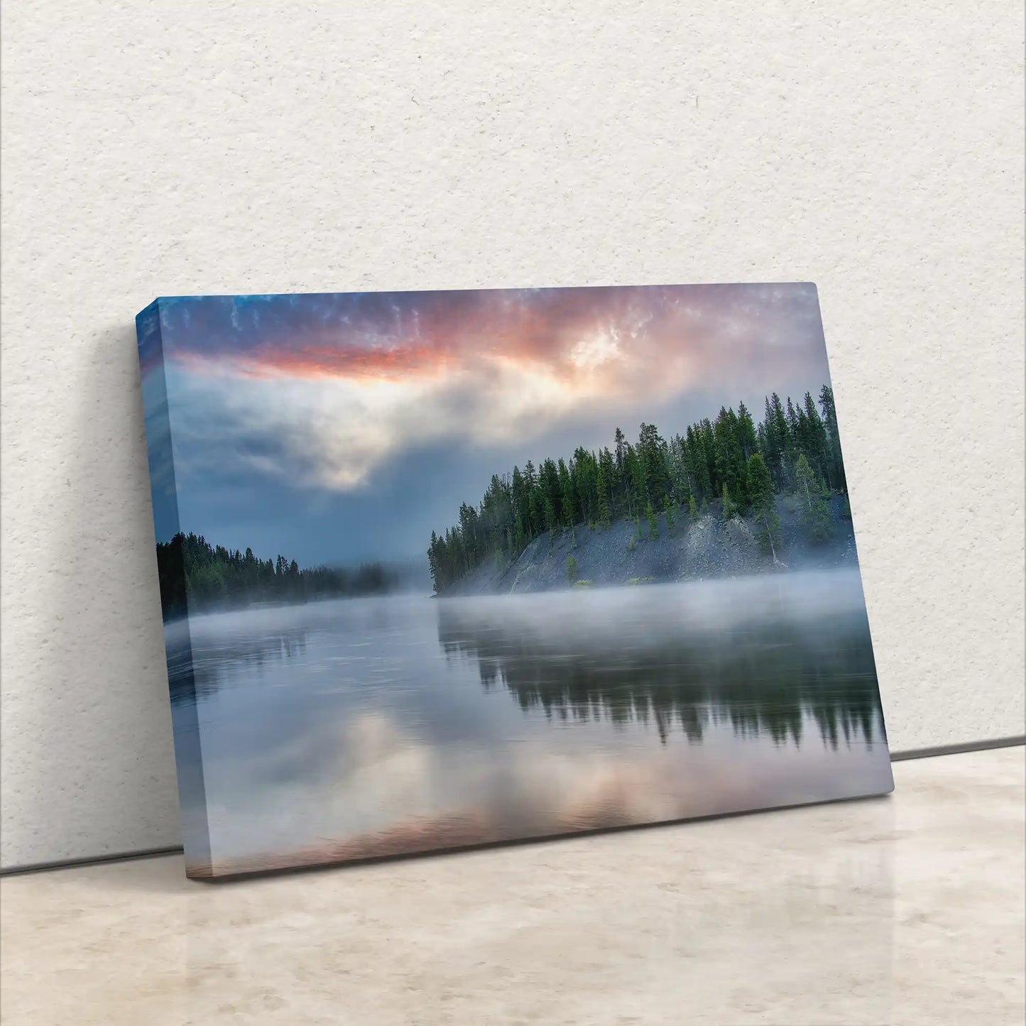 Canvas wall art leaning against a wall, depicting Yellowstone Lake Forest and its reflection under a stormy sunrise sky.