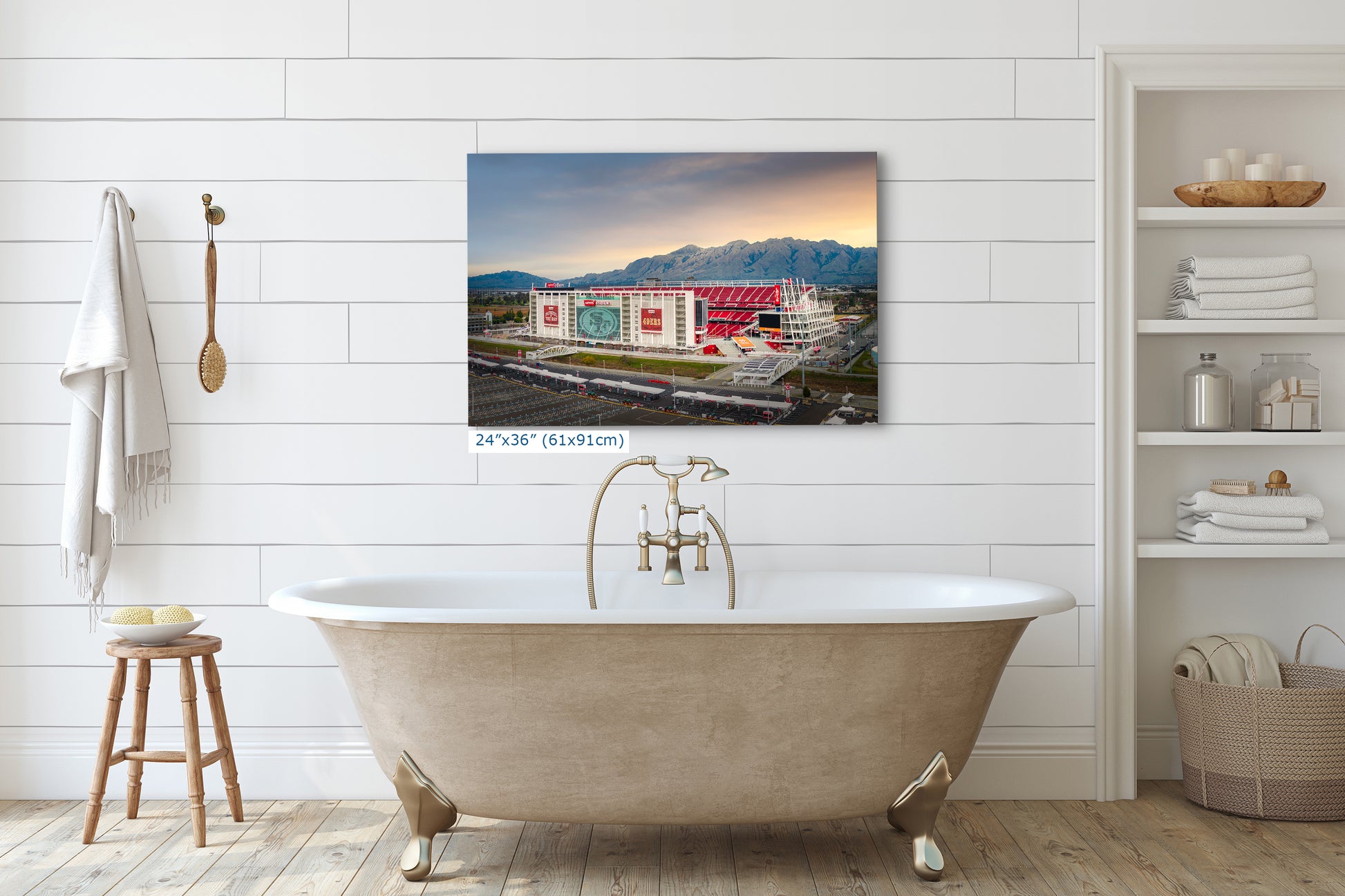 a large, white clawfoot bathtub in a bathroom setting, with a large framed photograph of a building in the background.