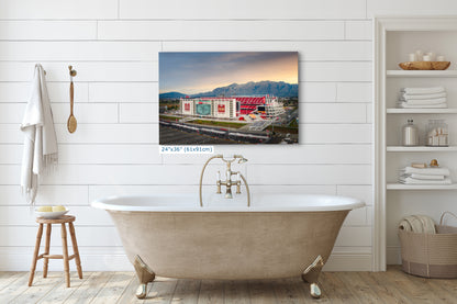 a large, white clawfoot bathtub in a bathroom setting, with a large framed photograph of a building in the background.