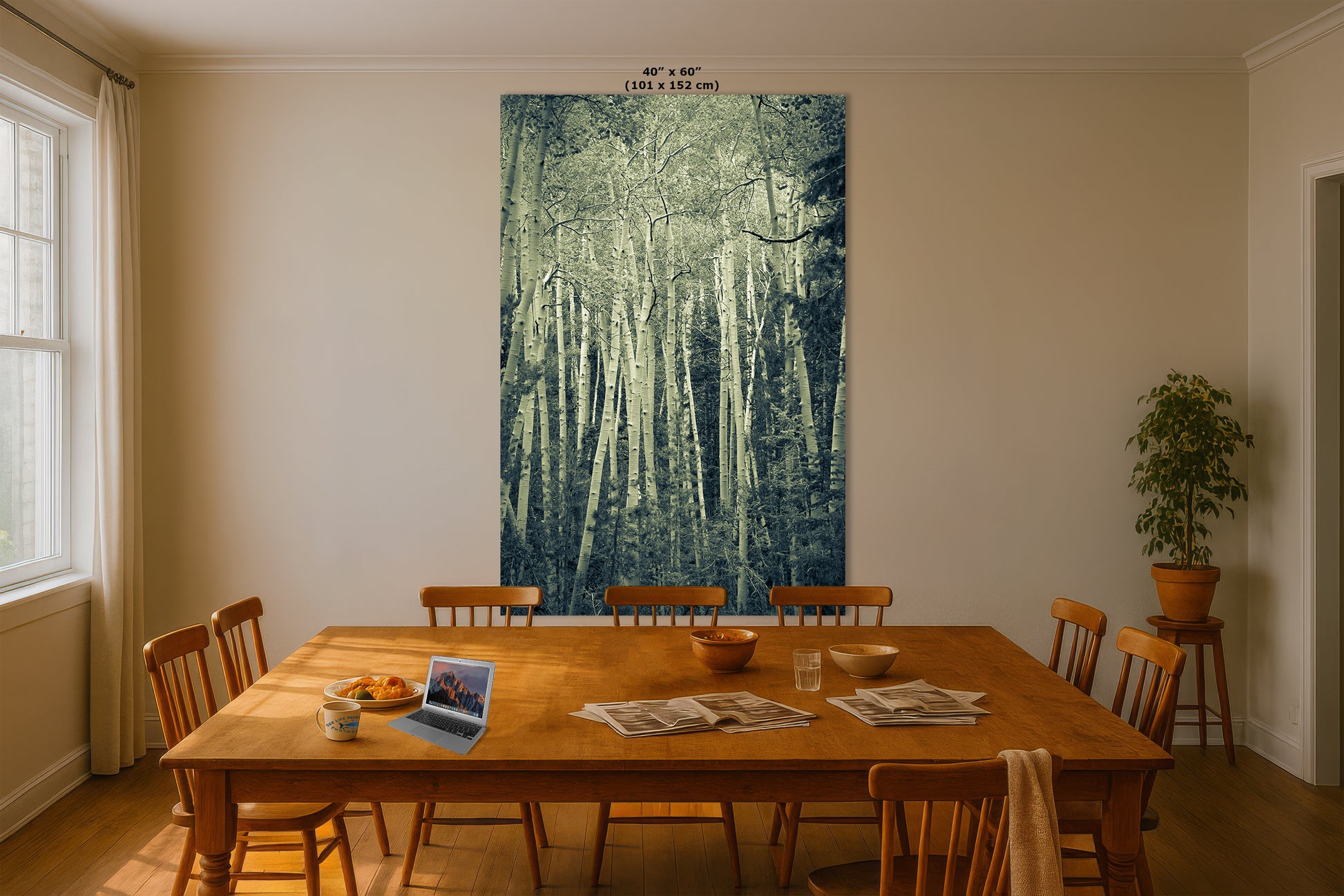 a dining room with a large wooden table surrounded by chairs. On the table, there is a laptop, a bowl, and a plate of food. The wall behind the table features a large painting of a forest scene.