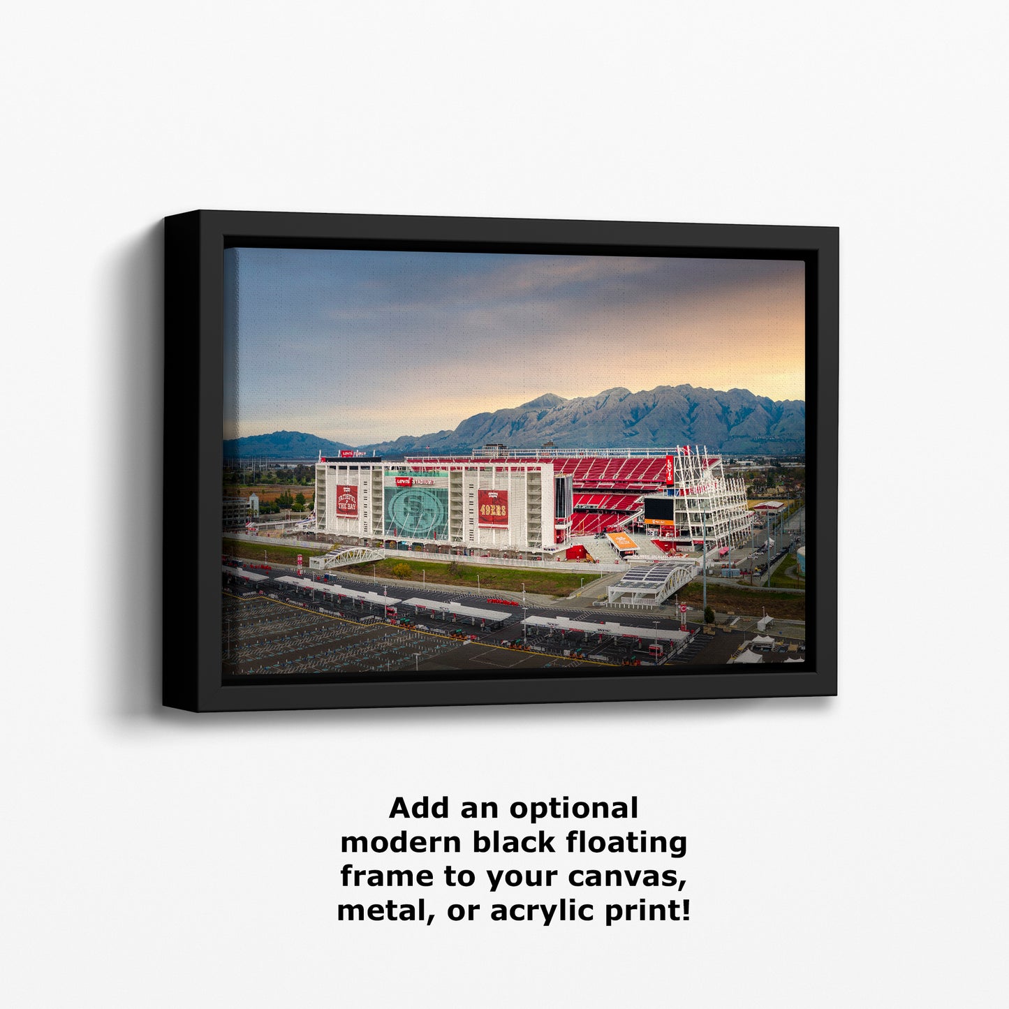 a large stadium with a mountainous backdrop, featuring a large advertisement on the side of the building.