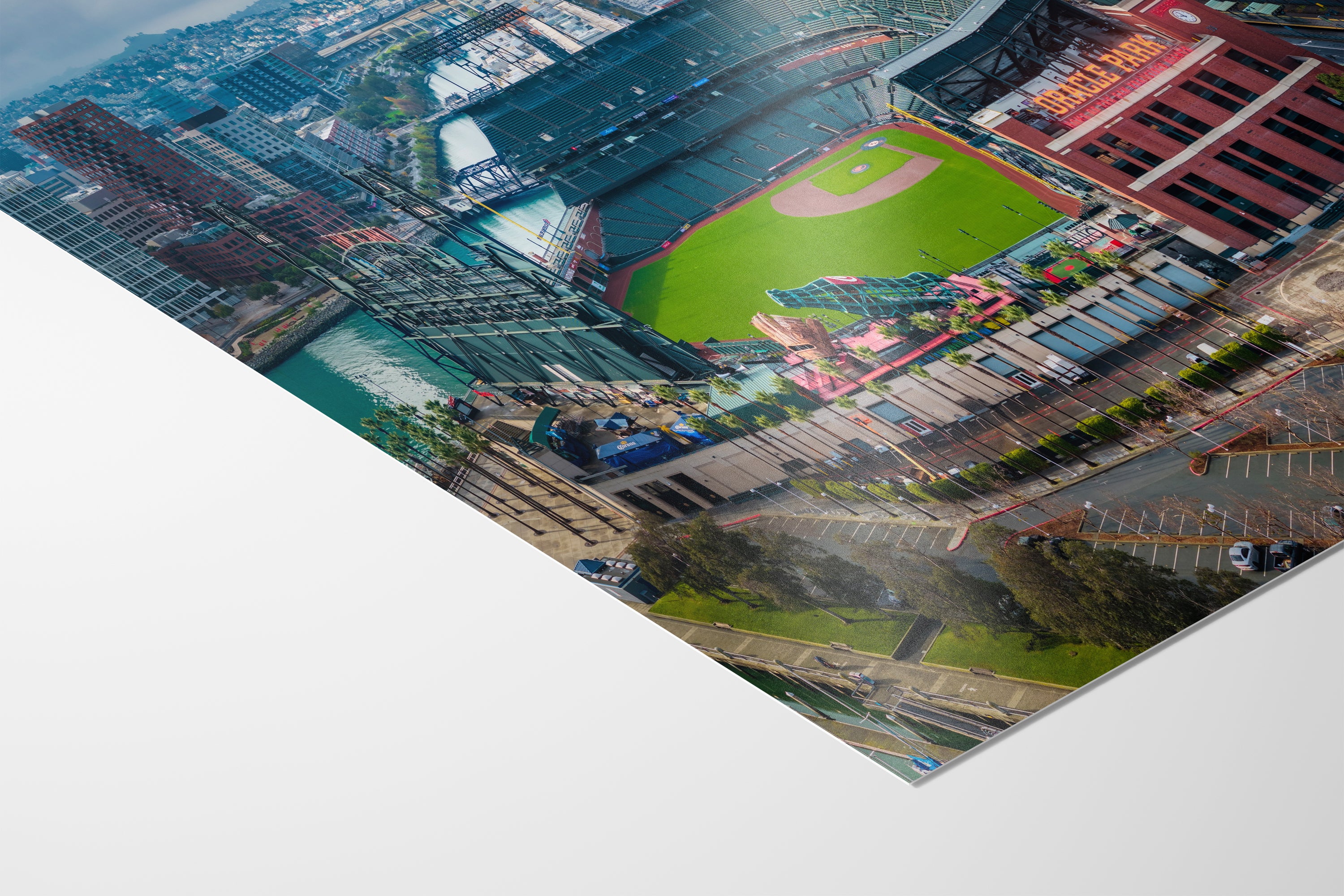 An aerial view of a baseball stadium and surrounding cityscape, with a mix of green and brown tones.