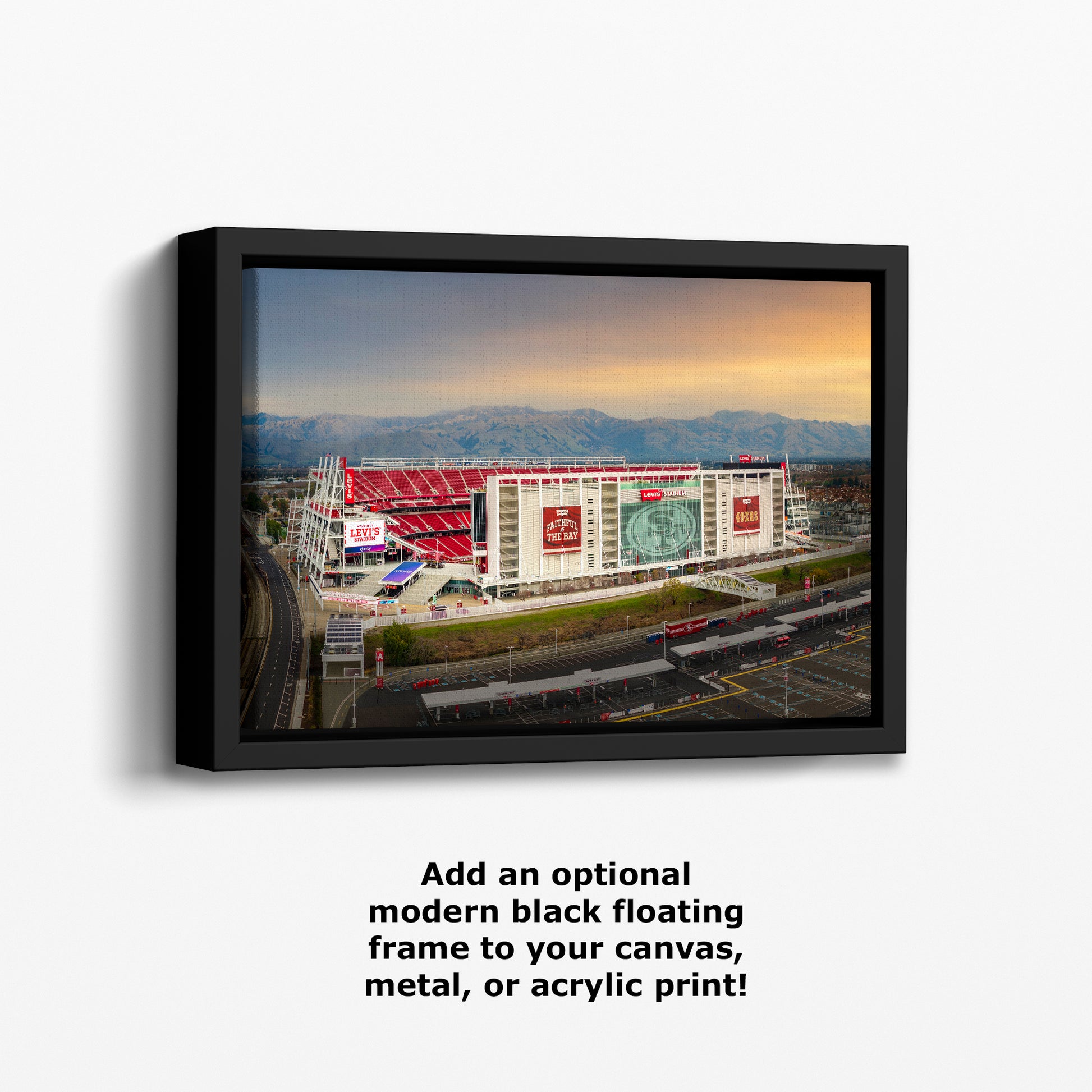 a large stadium with a red roof and multiple advertisements on its exterior, set against a backdrop of mountains and a clear sky.