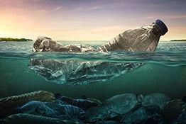 Image of a half-submerged plastic bottle in the ocean, highlighting underwater pollution and environmental impact.