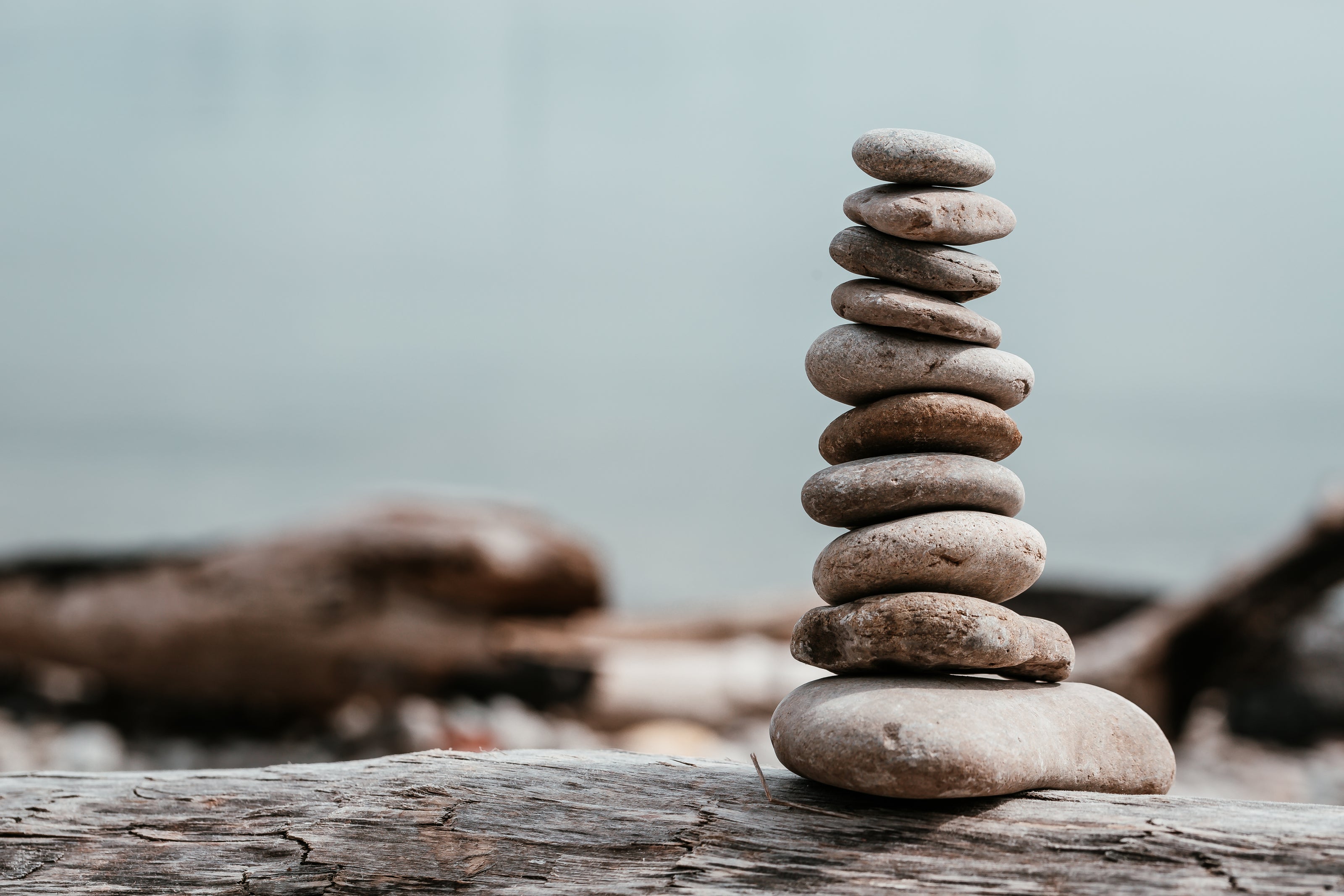 Zen-like stack of smooth stones balanced carefully on a weathered wooden surface by the sea.
